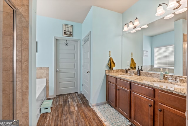 bathroom with a bath, hardwood / wood-style flooring, vanity, and a notable chandelier