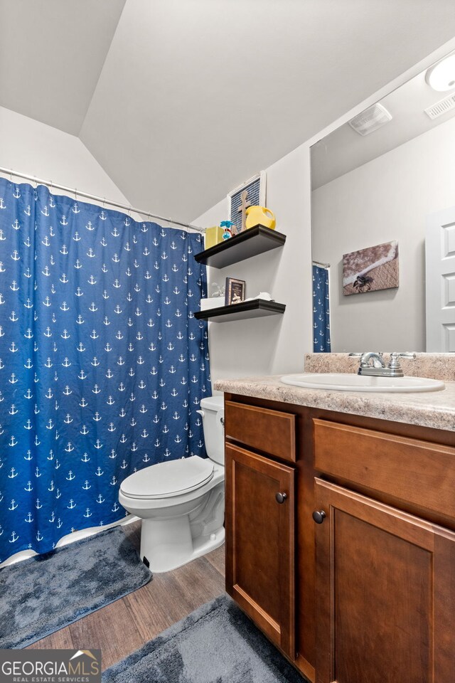 bathroom featuring toilet, vanity, vaulted ceiling, walk in shower, and wood-type flooring