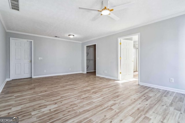 unfurnished room featuring ceiling fan, light wood-type flooring, crown molding, and a textured ceiling