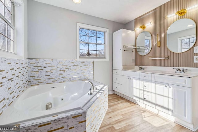 bathroom with tiled bath, vanity, and hardwood / wood-style flooring