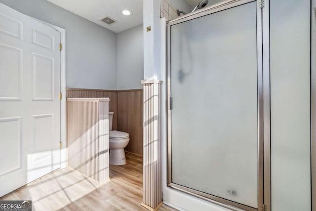 bathroom with hardwood / wood-style floors, toilet, and walk in shower