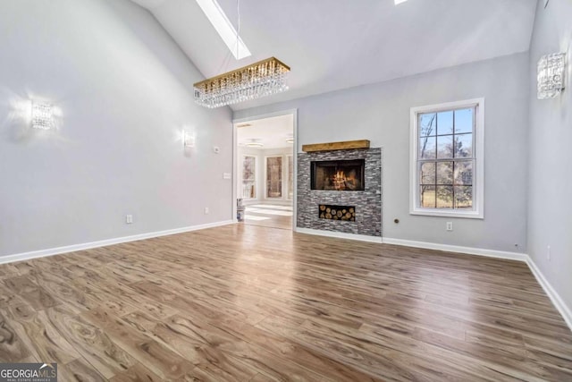 unfurnished living room featuring vaulted ceiling with skylight, wood-type flooring, and a fireplace