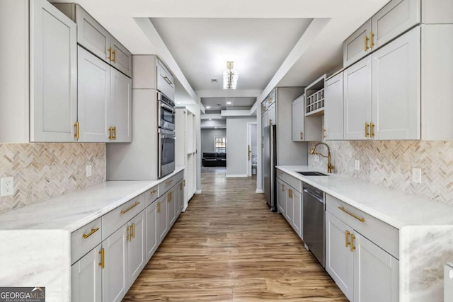 kitchen featuring a tray ceiling, sink, appliances with stainless steel finishes, and gray cabinets