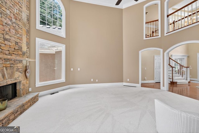 4225 Dunham Park, Flowery Branch, GA 30542 - unfurnished living room with a towering ceiling, a ceiling fan, carpet flooring, a stone fireplace, and stairway