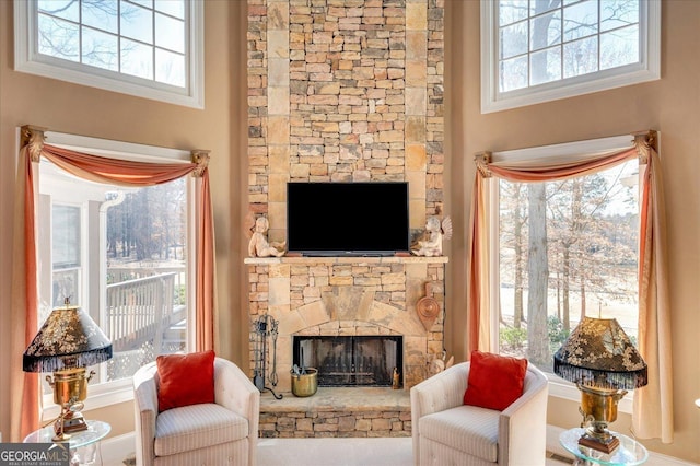 living room with a high ceiling and a stone fireplace