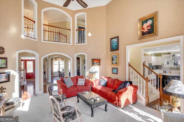 living room with ceiling fan, a high ceiling, and carpet