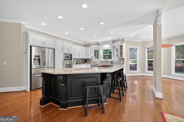 4225 Dunham Park, Flowery Branch, GA 30542 - kitchen with stainless steel appliances, white cabinetry, ornamental molding, a spacious island, and light wood-style flooring