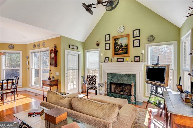 living room featuring a high end fireplace, light hardwood / wood-style flooring, and high vaulted ceiling