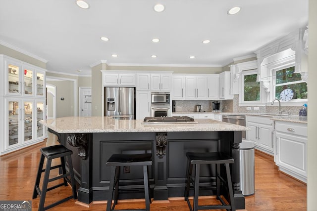 4225 Dunham Park, Flowery Branch, GA 30542 - kitchen with stainless steel appliances, white cabinets, a spacious island, tasteful backsplash, and a breakfast bar area