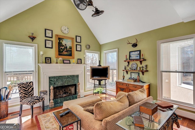 living room featuring high vaulted ceiling, a premium fireplace, and light wood-type flooring