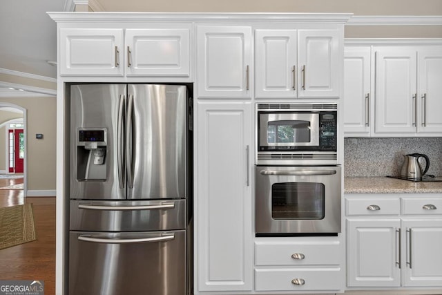 4225 Dunham Park, Flowery Branch, GA 30542 - kitchen featuring stainless steel appliances, arched walkways, white cabinets, wood finished floors, and ornamental molding