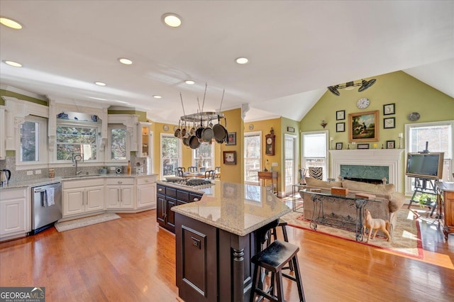 kitchen with white cabinetry, appliances with stainless steel finishes, a kitchen breakfast bar, lofted ceiling, and a center island