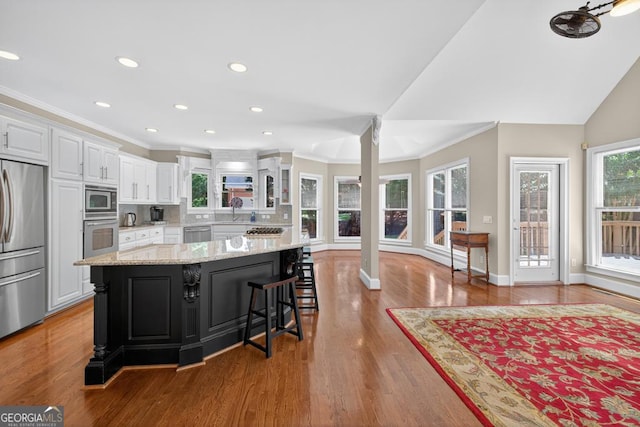 4225 Dunham Park, Flowery Branch, GA 30542 - kitchen featuring built in appliances, white cabinetry, ornamental molding, a breakfast bar, and a kitchen island