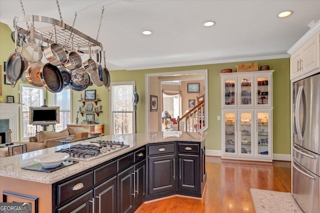 kitchen featuring a center island, a premium fireplace, white cabinetry, ornamental molding, and stainless steel appliances