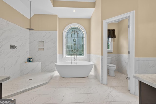 4225 Dunham Park, Flowery Branch, GA 30542 - bathroom with marble look tile flooring, a freestanding bath, wainscoting, tile walls, and vanity
