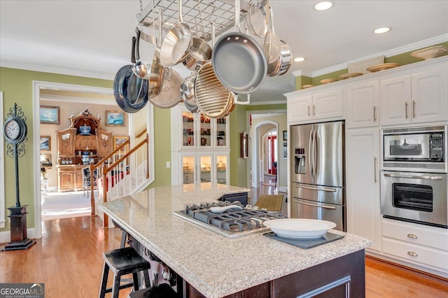 kitchen with appliances with stainless steel finishes, crown molding, white cabinetry, and a kitchen island