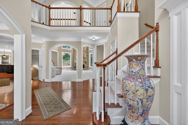 4225 Dunham Park, Flowery Branch, GA 30542 - foyer entrance featuring arched walkways, stairs, a high ceiling, wood finished floors, and ornamental molding