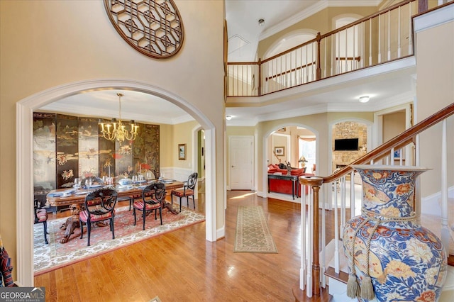 foyer entrance with a chandelier, crown molding, a towering ceiling, and hardwood / wood-style floors