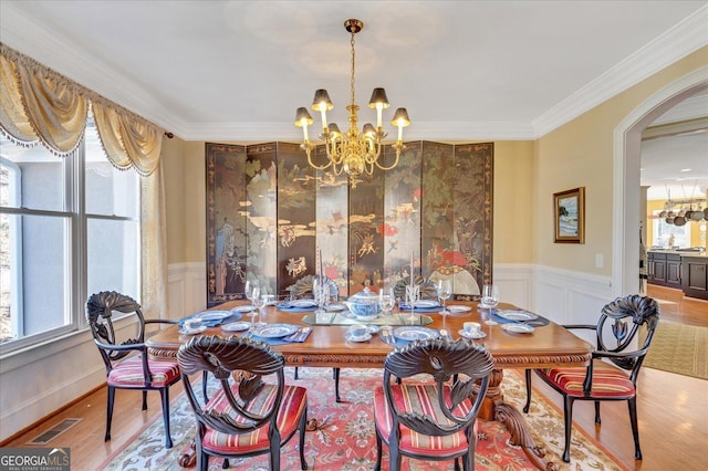 dining room featuring a wealth of natural light, crown molding, wood-type flooring, and a notable chandelier