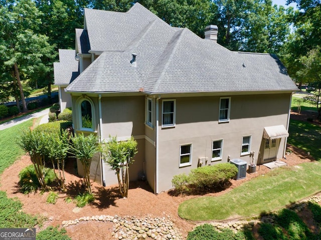 4225 Dunham Park, Flowery Branch, GA 30542 - view of home's exterior with a shingled roof, stucco siding, a chimney, and a lawn