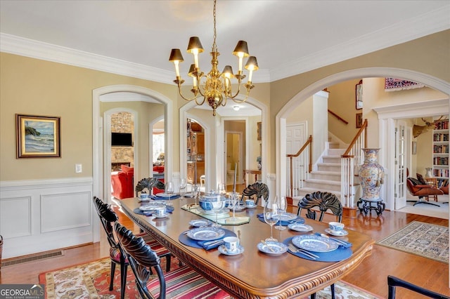 dining space with hardwood / wood-style floors, a chandelier, and ornamental molding