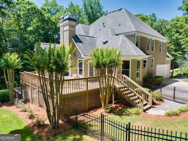 4225 Dunham Park, Flowery Branch, GA 30542 - back of property featuring roof with shingles, a garage, a chimney, stucco siding, and a deck