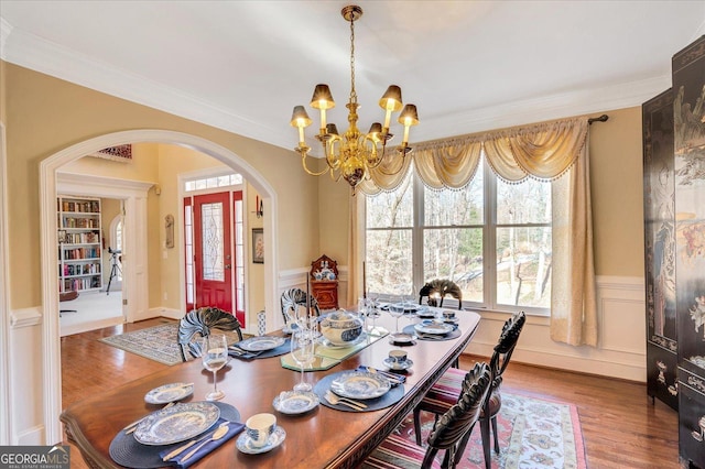 dining space featuring an inviting chandelier, ornamental molding, and hardwood / wood-style floors