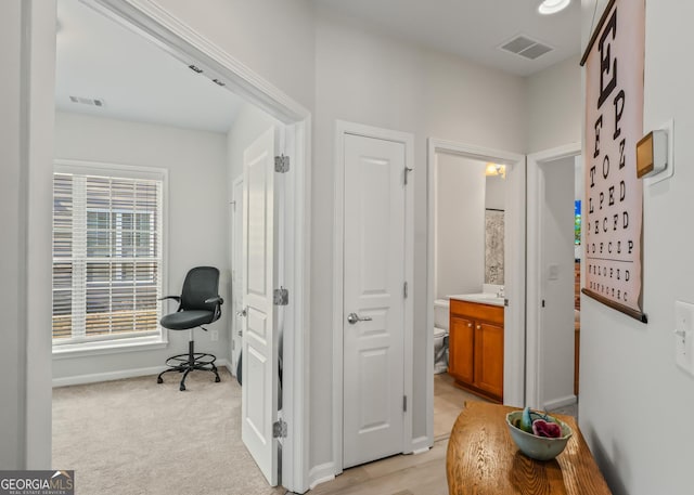 corridor with light carpet and sink