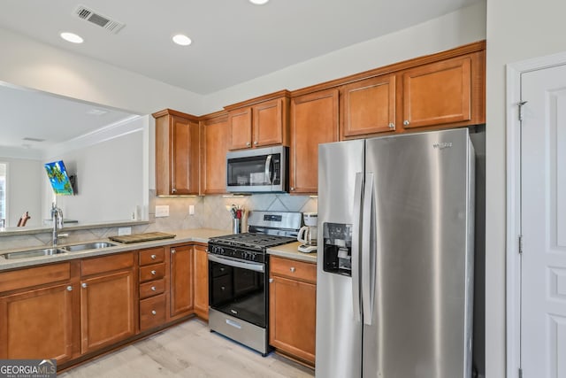 kitchen with light hardwood / wood-style floors, sink, backsplash, and stainless steel appliances