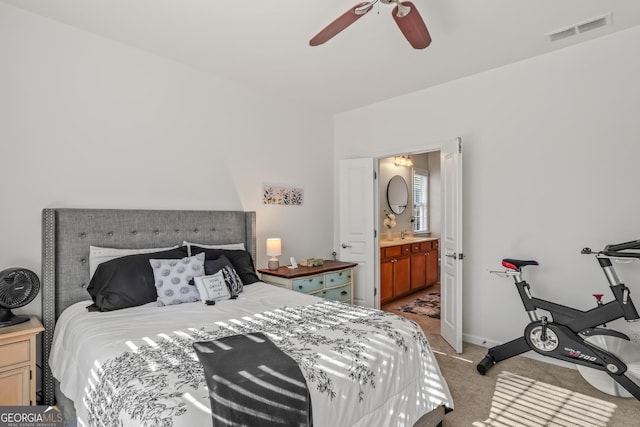 bedroom featuring ceiling fan, ensuite bath, and light carpet