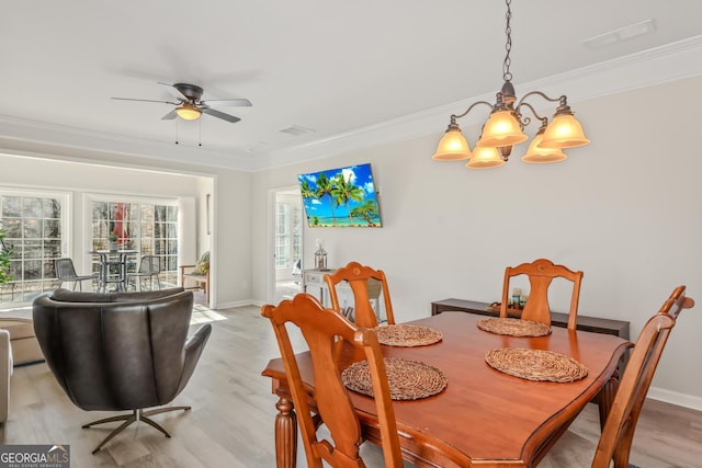 dining space with light wood-type flooring, ornamental molding, and ceiling fan with notable chandelier