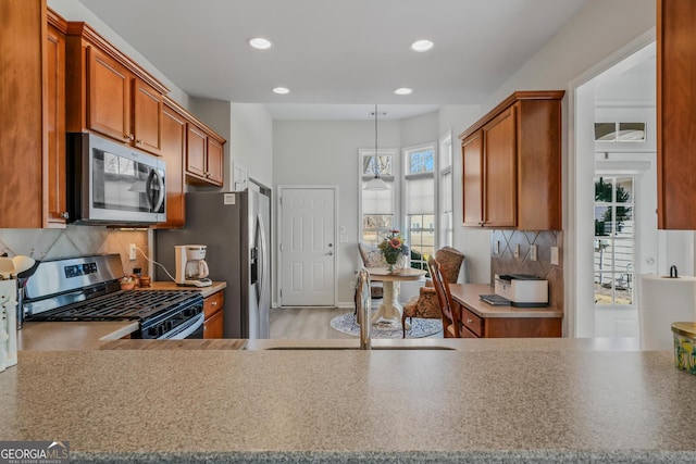 kitchen featuring decorative light fixtures, sink, backsplash, and appliances with stainless steel finishes