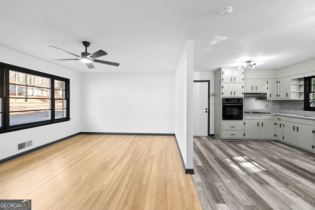 kitchen with ceiling fan, extractor fan, light hardwood / wood-style floors, black appliances, and decorative backsplash