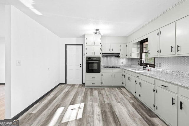 kitchen featuring light stone countertops, black appliances, white cabinetry, sink, and backsplash