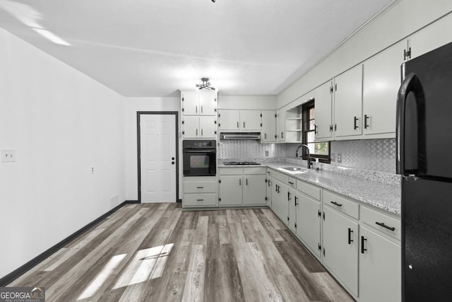 kitchen featuring black appliances, white cabinetry, tasteful backsplash, light hardwood / wood-style floors, and sink