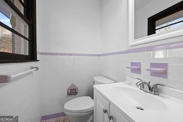 bathroom with tile walls, toilet, and vanity