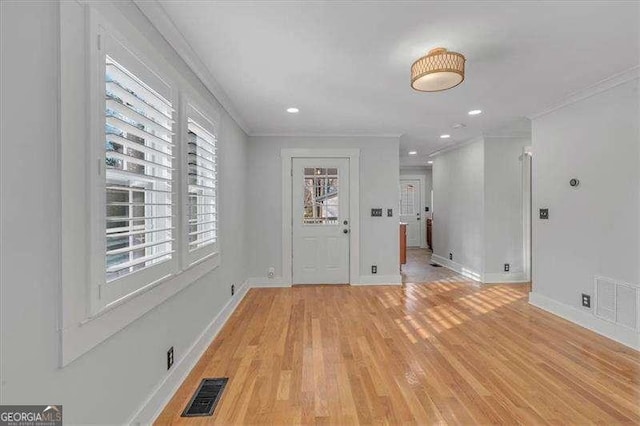 foyer entrance with a healthy amount of sunlight, crown molding, and light hardwood / wood-style floors