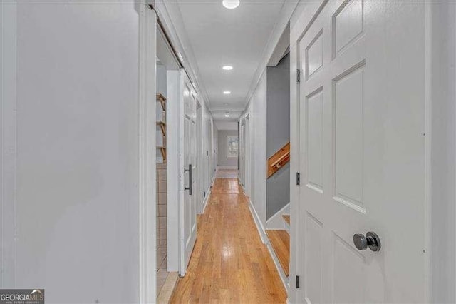 corridor with light wood-type flooring and crown molding