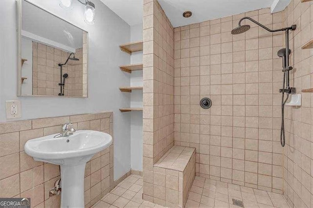 bathroom with tile walls, tile patterned flooring, and a tile shower