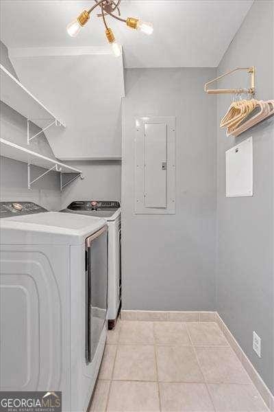 clothes washing area with light tile patterned floors, electric panel, a notable chandelier, and independent washer and dryer