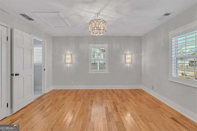 unfurnished room with light wood-type flooring and a chandelier