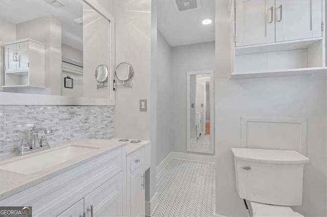 bathroom featuring toilet, decorative backsplash, tile patterned floors, and vanity