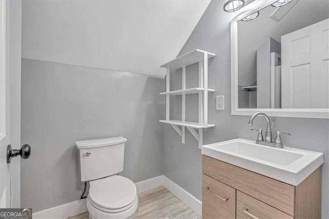 bathroom with toilet, vanity, and vaulted ceiling