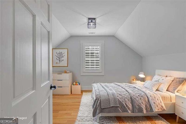 bedroom with lofted ceiling and light wood-type flooring