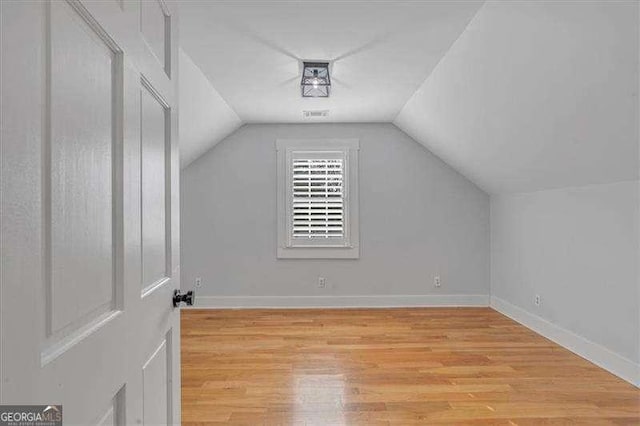 bonus room featuring light wood-type flooring and vaulted ceiling