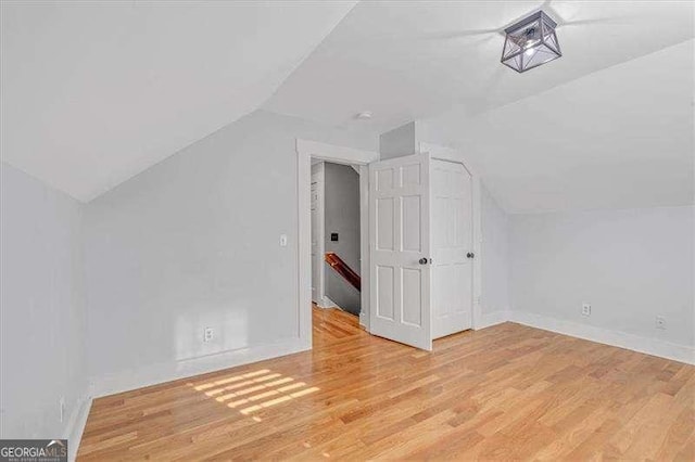 bonus room with light wood-type flooring and vaulted ceiling