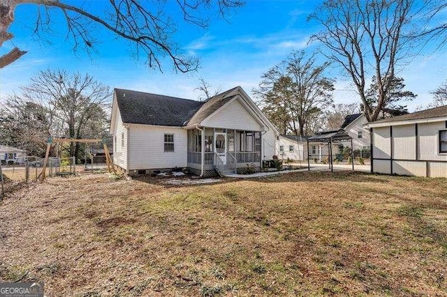 rear view of house featuring a sunroom and a lawn