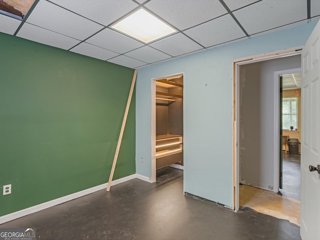 unfurnished bedroom featuring a spacious closet, a paneled ceiling, and a closet