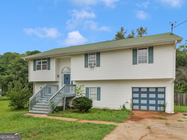 raised ranch with a front lawn, cooling unit, and a garage