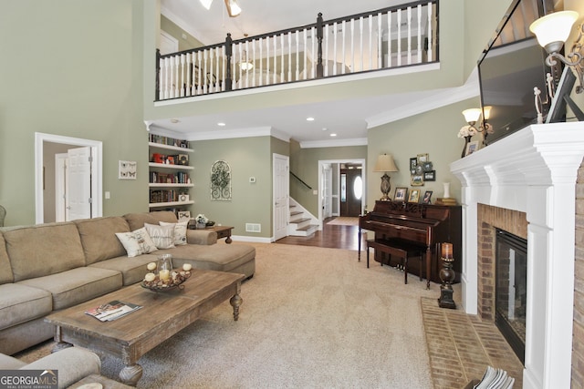 carpeted living room with crown molding, a fireplace, and a high ceiling